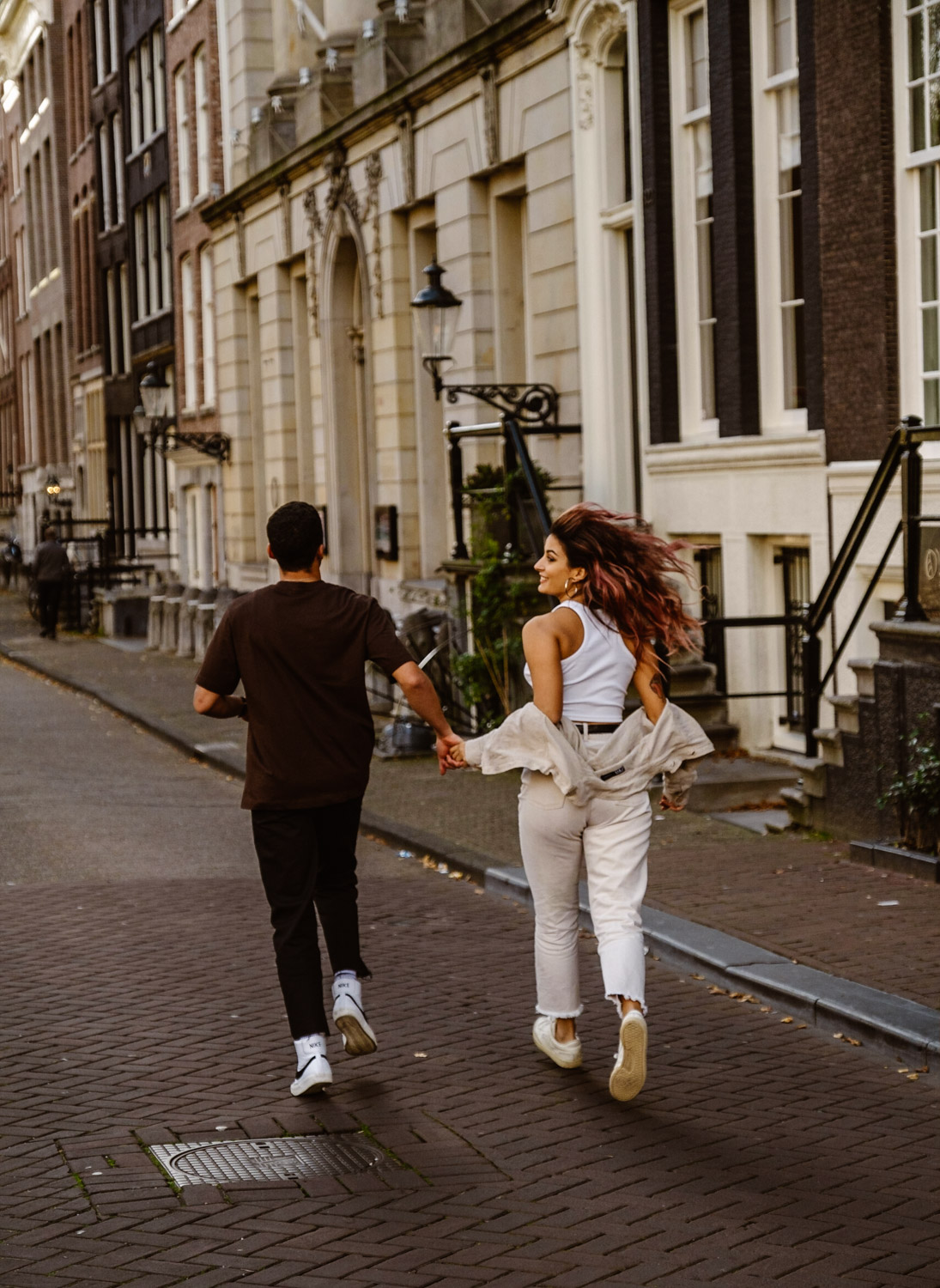 Couple running and holding hands in the streets of Amsterdam.
