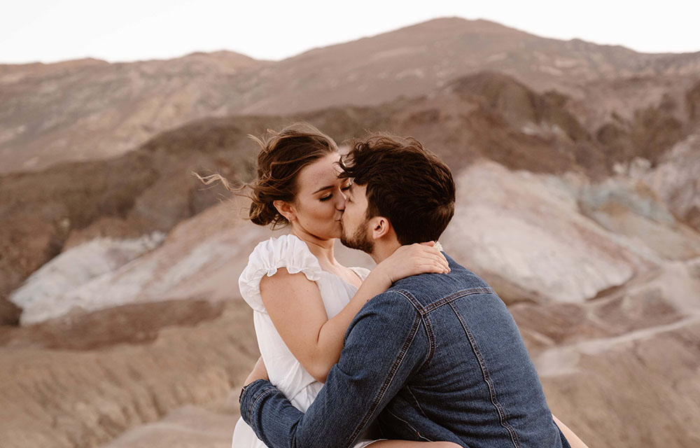 The couple shares a kiss with the multi-colored hills of Artist's Palette as their backdrop.