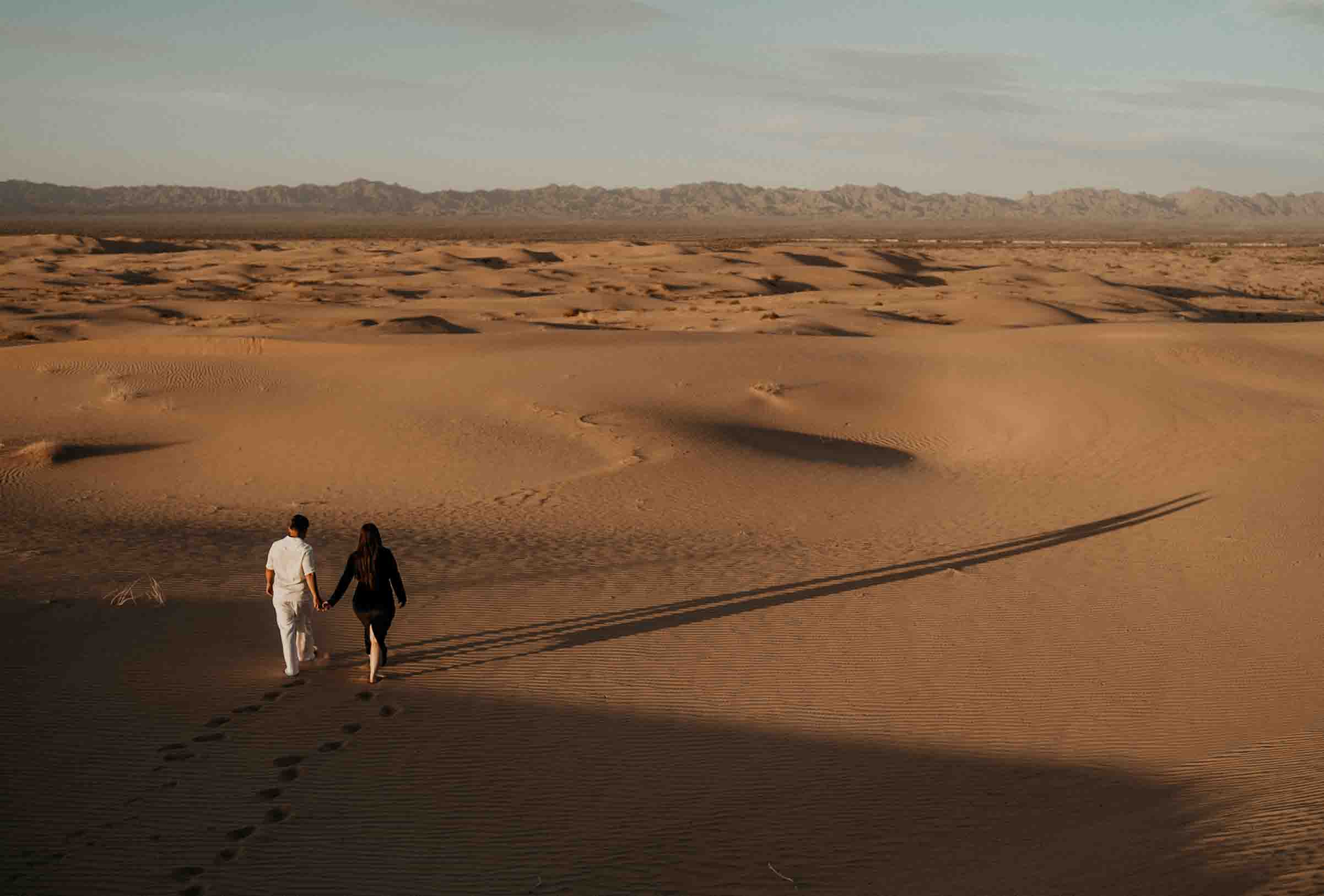 The couple walks hand-in-hand with long shadows at the Imperial Sand Dunes.