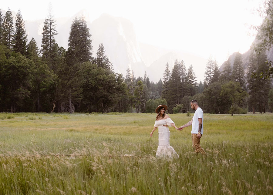 Couple walking hand in hand through a meadow in Yosemite Valley.
