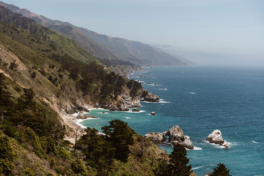 Overlooking the Big Sur coastline with turquoise water, rugged cliffs, and trees along the shore.